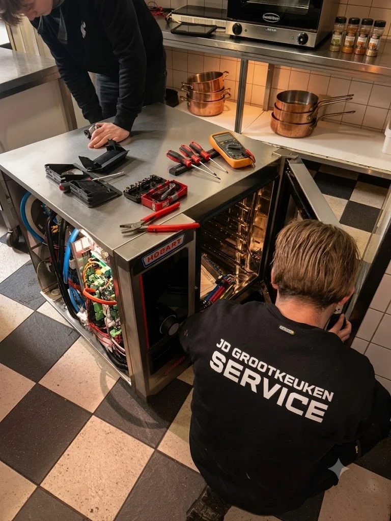 Monteur van JD Grootkeukenservice aan het werk bij een Hobart-combisteamer